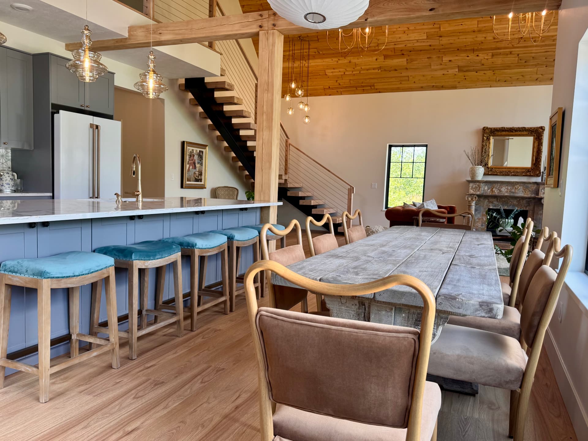 The long dining table opening onto the kitchen under vaulted ceilings