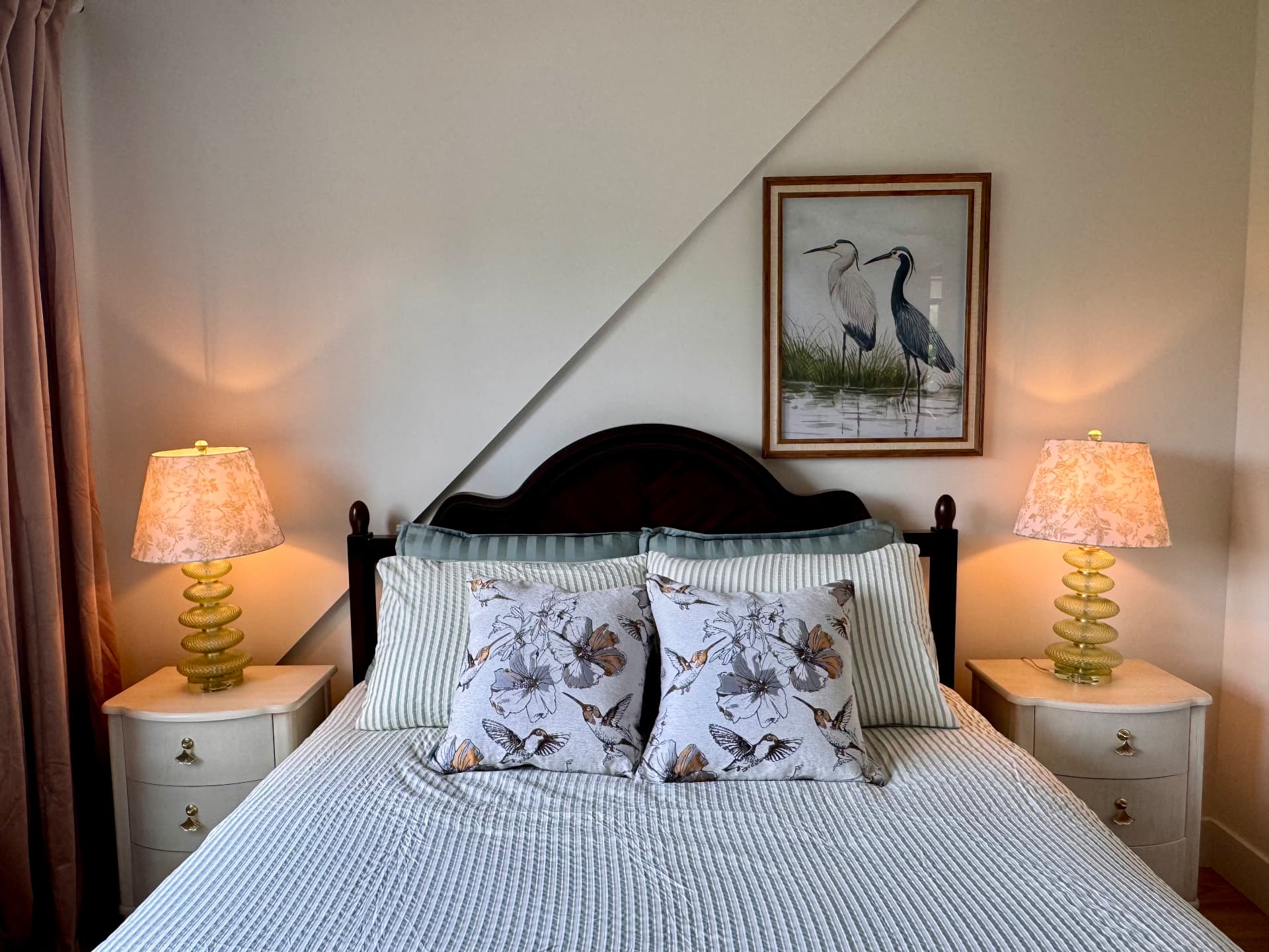 A bedroom flanked by matching lamps and a heron painting