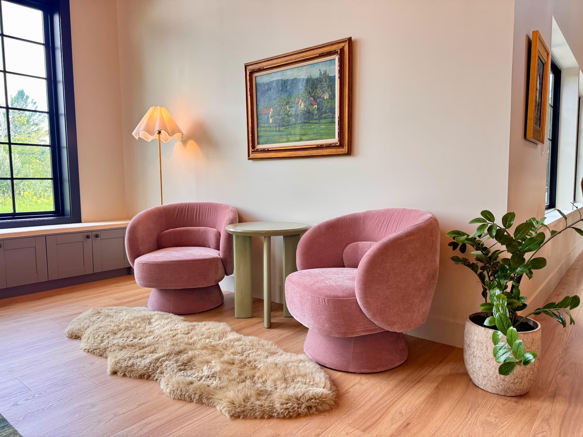 A sitting nook with velvet chairs and a field painting