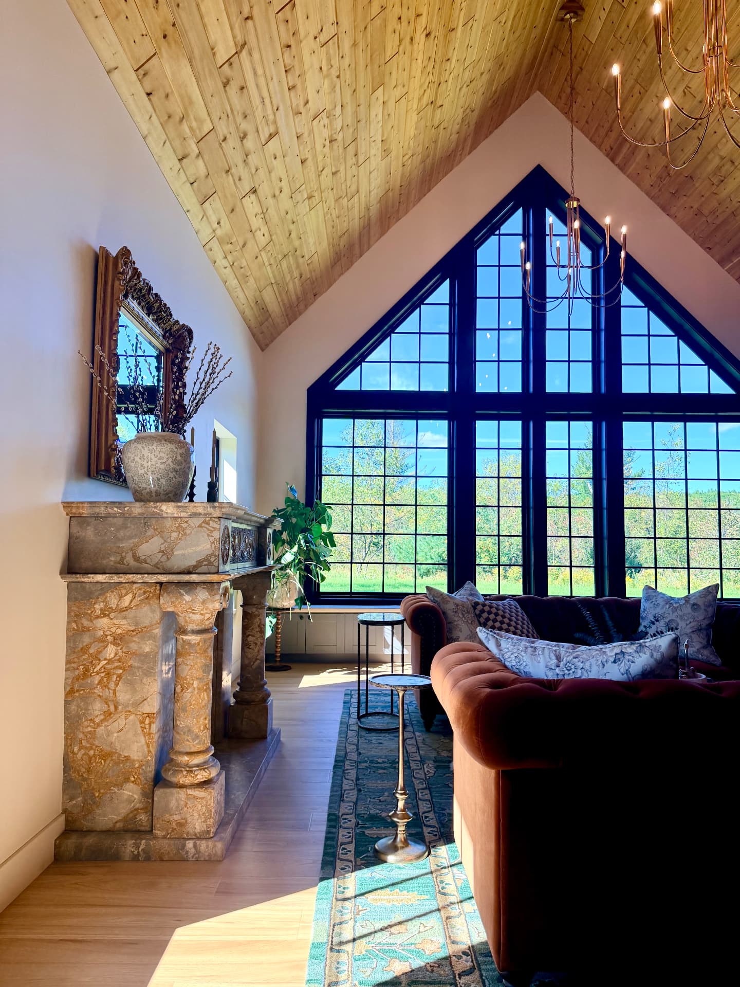 The vaulted great room and its tall gabled window looking out to the trees