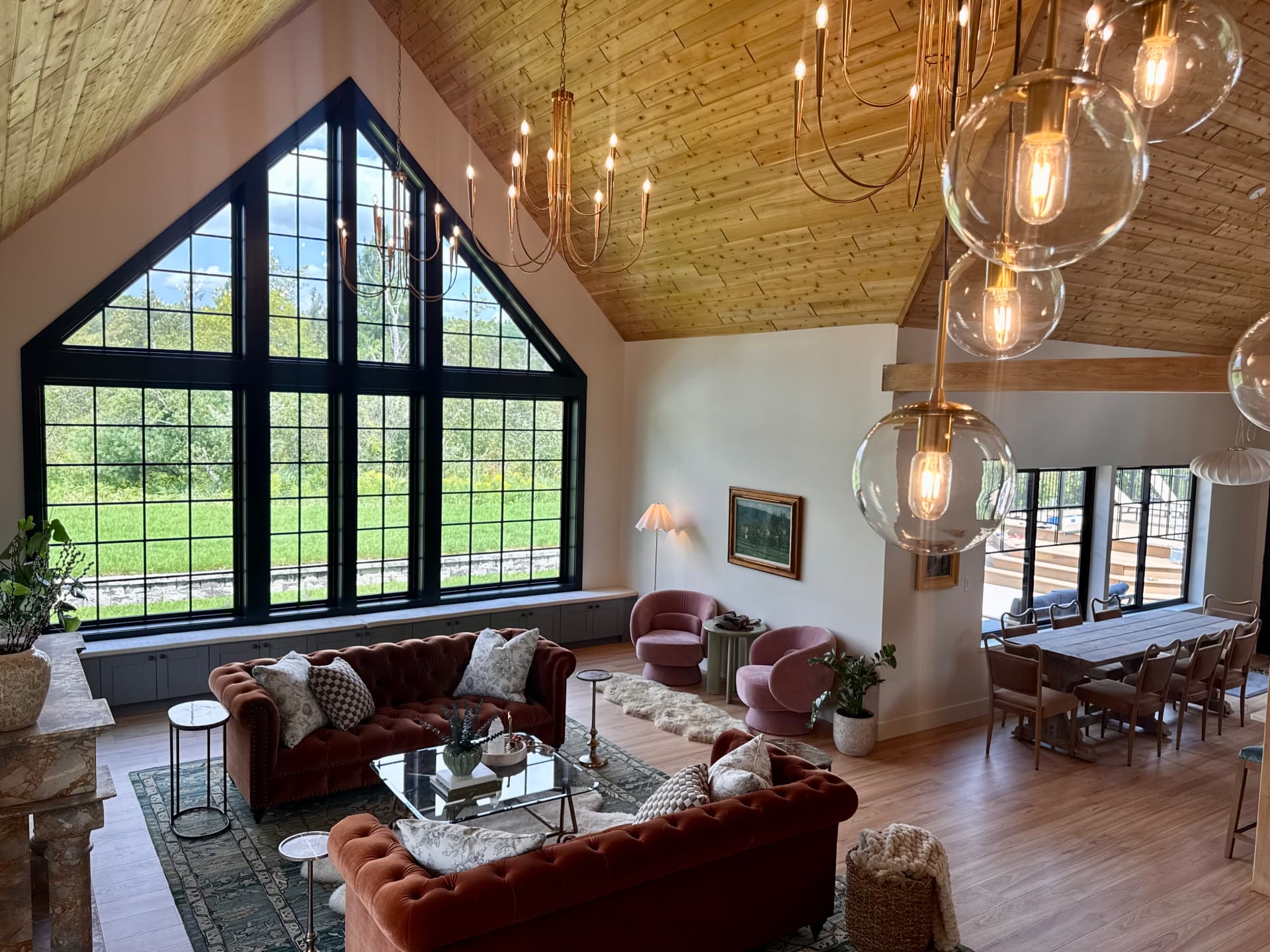 The great room beneath a vaulted wood ceiling, chandeliers lit