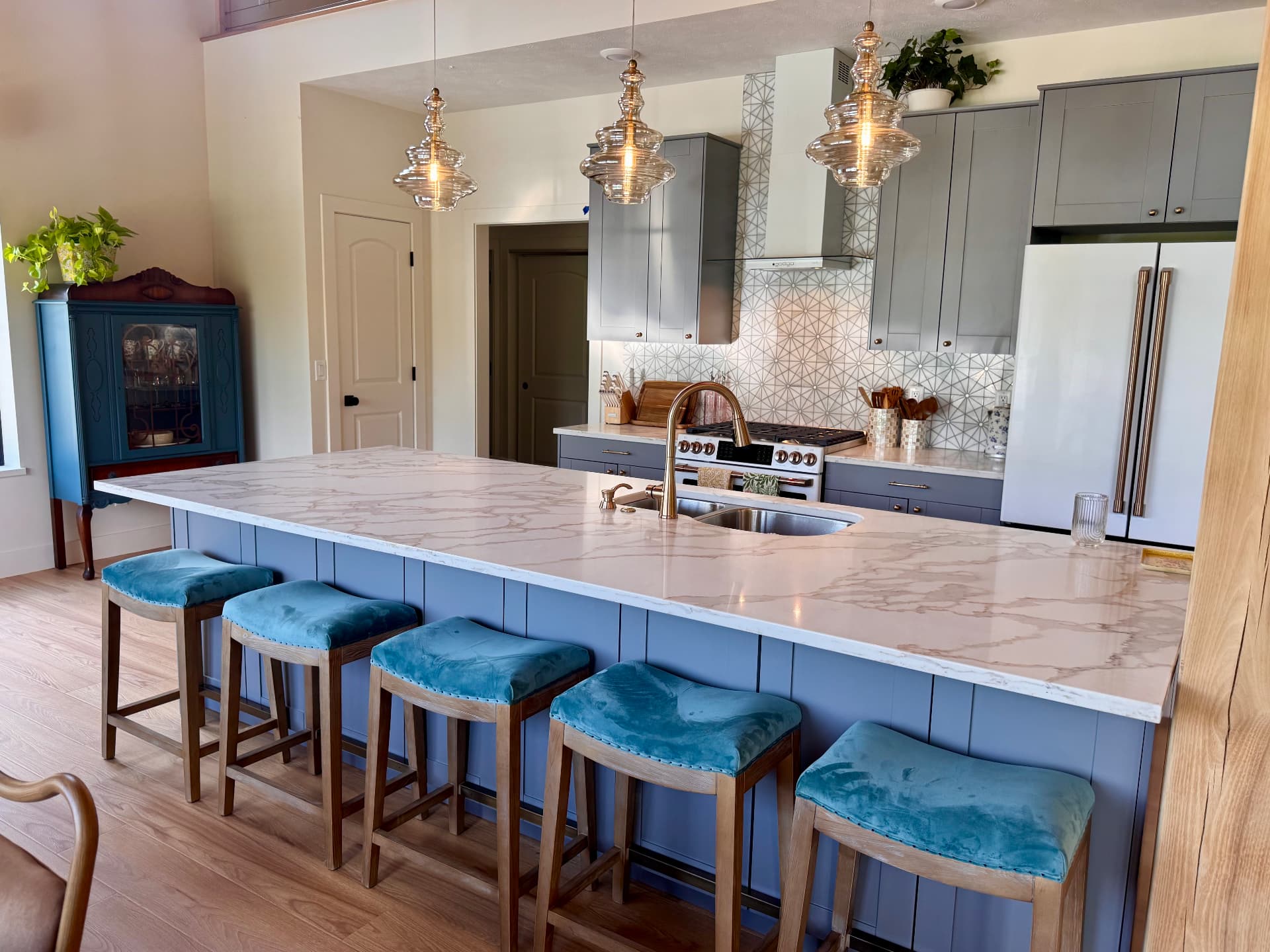 The kitchen island with marble top and teal stools
