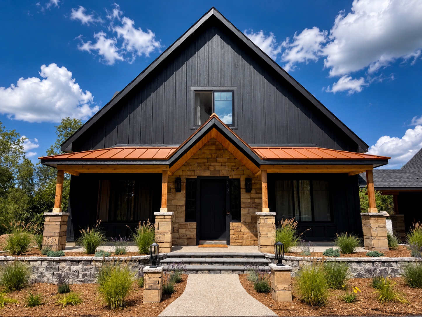 The front of the house under a bright summer sky, stone porch and copper roof